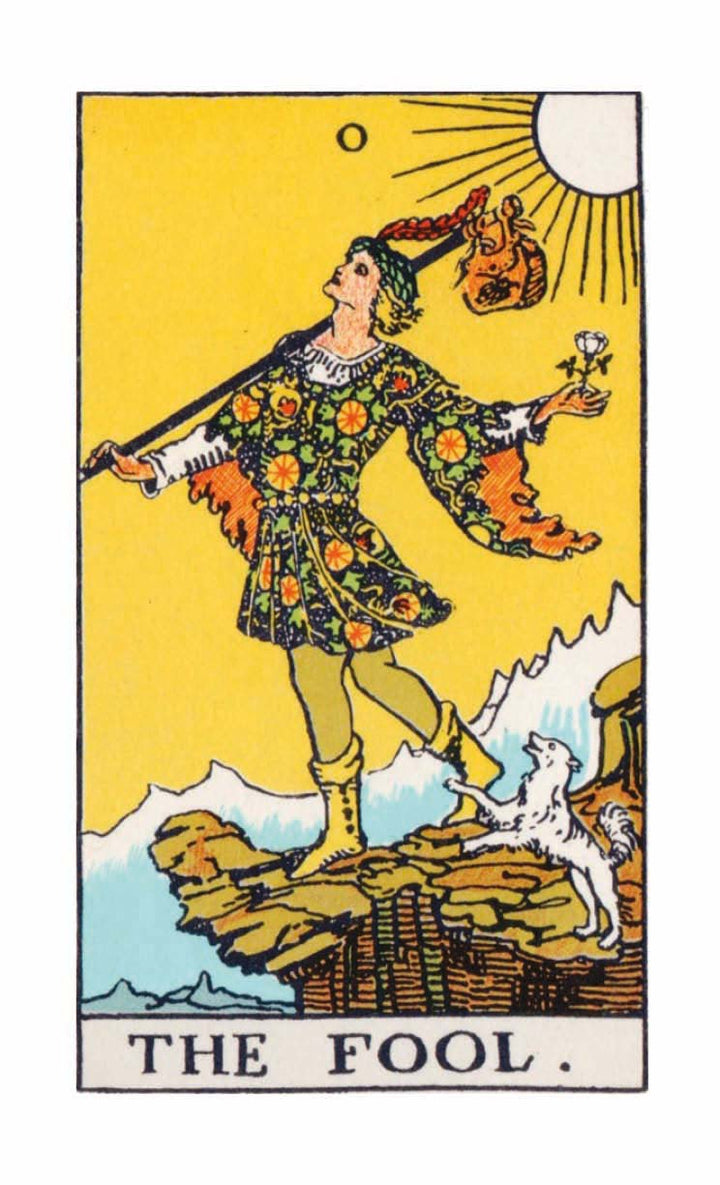 A card from The Time Changer's Tarot by Schiffer Publishing, Ltd. depicts The Fool—a youth on a clifftop with a wand and sack, white rose, dog companion, sunlit yellow sky, and snowy mountains in the background.