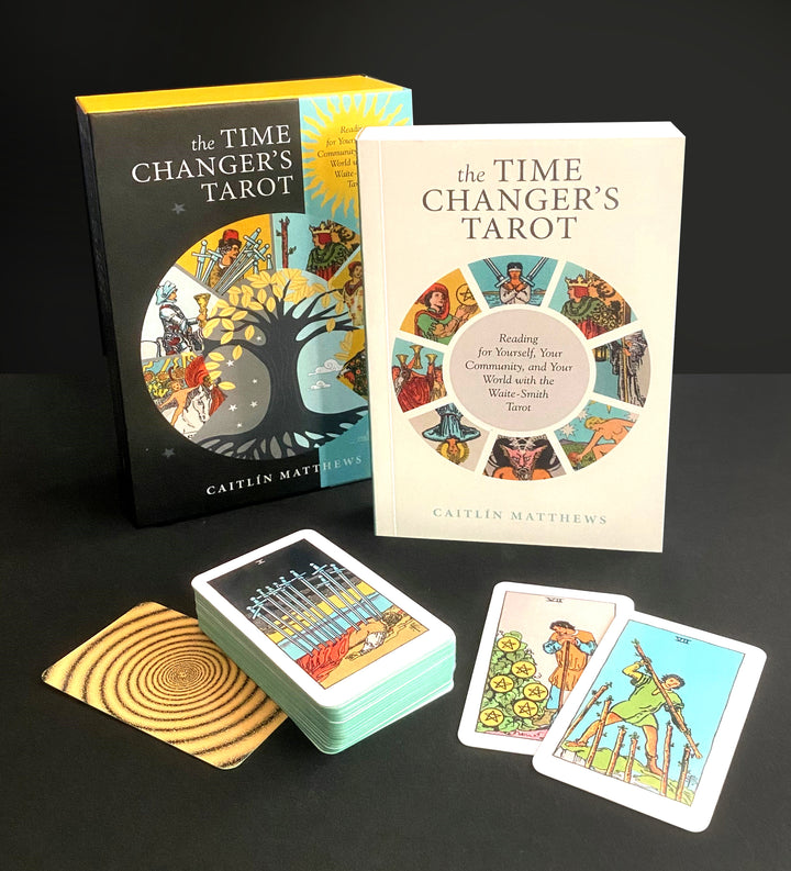 The Time Changer's Tarot by Schiffer Publishing, Ltd. is displayed with its modern tarot deck partially spread, two individual cards, and a wooden square on a black surface.
