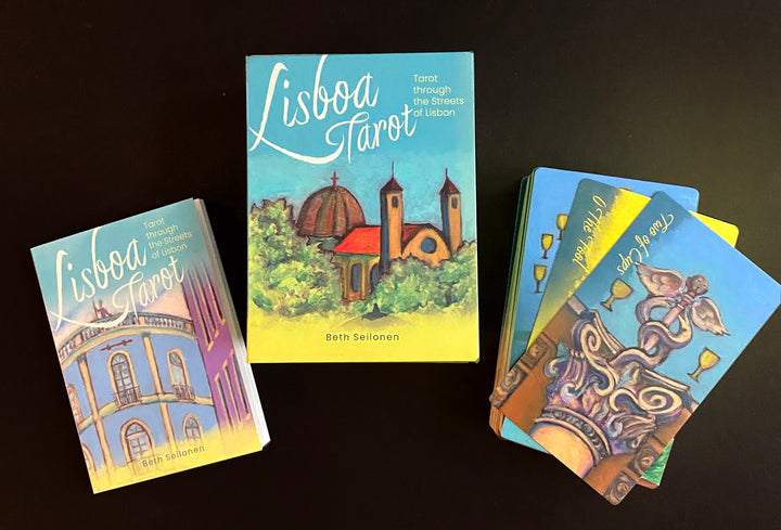The Lisboa Tarot by Schiffer Publishing, Ltd. is displayed on a black surface, featuring colorful cards inspired by Lisbon, Portugal and a guidebook adorned with iconic city architecture and Old World European charm.