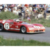 A red Alfa Romeo, number 12, races down the track with a helmeted driver, as a blurred crowd watches from the grass—capturing the legacy featured in Schiffer Publishing, Ltd.'s Alfa Romeo.