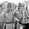 A man in dark clothing inspects young soldiers standing at attention outdoors with tents behind them—a scene from The Fighting Fathers by Schiffer Publishing, Ltd.