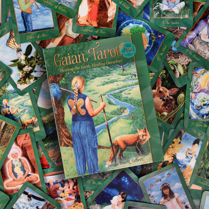 The Gaian Tarot by Schiffer Publishing, Ltd. is displayed with its box in the center, featuring a woman with a staff, butterfly wings, and a fox, surrounded by vibrant earth-inspired tarot cards.
