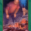 A man in a red shirt kneels by a campfire at night in the forest, with a cat nearby and the moon above. The Guardian of Fire card from the Gaian Tarot by Schiffer Publishing, Ltd. symbolizes earth-centered spirituality.