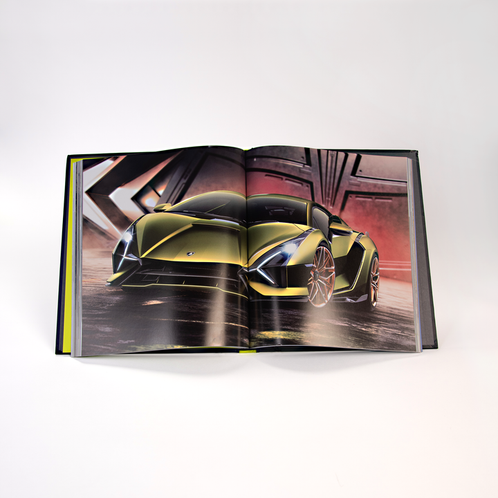 An open copy of Automobili Lamborghini by Schiffer Publishing, Ltd. reveals a full-page photo of a sleek, metallic green sports car with angular lines and dramatic lighting, set against geometric metal structures for a striking modern effect.