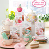 A vibrant array of Schiffer Publishing, Ltd.'s Crochet Cafe Amigurumi Kit Cupcake is styled with yarn on pastel plates. A floral teapot and teacup set decorate the background. Text: Collect the whole set!.