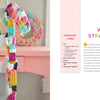 A vibrant woven straw chain from “Handmade Happiness Yarn Crafts” by Schiffer Publishing, Ltd. decorates a white chair. Beside it lies a printed guidebook with instructions on a white and pink background.
