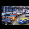 Schiffer Publishing, Ltd.'s Audi's Historic Fleet showcases a blue and yellow vintage NSU race car with Continental logos, displayed in a bright garage among classic cars at the Audi Museum Mobile.