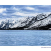 A frozen, blue Jackson Lake with a visible ice crack lies beneath the snow-capped Teton Range under cloudy skies in Grand Teton National Park. © Schiffer Publishing, Ltd.