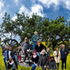 A group of photographers poses in front of a truck parked in a field of yellow flowers under a large oak tree, in a scene from the Schiffer Publishing, Ltd. book Los Angeles.