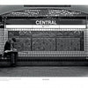 A person sits alone on a bench at Central station, reading a newspaper—a quiet moment featured in "Boston Below" by Schiffer Publishing, Ltd., capturing classic T-riders on the Boston MBTA subway amid patterned tiles and signs.