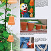 Create a fun autumn garden project for kids with step-by-step photos from *Kinder Gardens: Autumn Fun* by Schiffer Publishing, Ltd.—learn to make stacked clay pots hanging on a string, perfect for outdoor activities among leafy green plants.