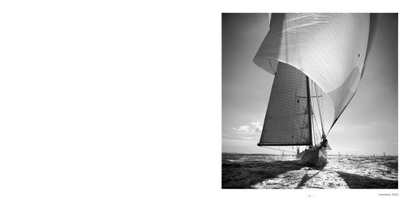 Black-and-white photography in "Sailboats" by Schiffer Publishing, Ltd. captures a classic sailboat with sunlit sails gliding across the water against a cloudy sky, reminiscent of Michael Kahn's evocative style.