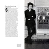 A black-and-white photo of a man and woman in formal wear with flowers, leaning against a wall featuring the bold "Poster Man" graphic from Schiffer Publishing, Ltd., echoing Push Pin Studios’ protest against conformity.