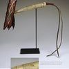 Schiffer Publishing, Ltd.’s Native American Horse Gear showcases a 19th-century ivory quirt with a red and black leather handle, engraved ivory body (close-up shown), and a long leather strap, displayed elegantly on a stand.
