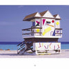 The South Beach Lifeguard Stations by Schiffer Publishing, Ltd. features a white stand with colorful geometric shapes on a sandy beach, turquoise ocean, and clear blue sky—ideal for capturing classic South Beach photography.