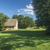 The book "Plain Meetinghouses" by Schiffer Publishing, Ltd. features a small stone house with a pitched roof amid green grass, tall trees, and corn beneath Lancaster County skies; early Mennonite meetinghouse facts are displayed on a beige panel to the right.