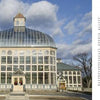 Wide-angle photo of the Howard Peters Rawlings Conservatory, a grand Victorian glass greenhouse beneath a partly cloudy sky, with text about Maryland's Public Gardens & Parks from Schiffer Publishing, Ltd. on the right.
