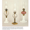 Three antique kerosene lamps with glass fonts and tall chimneys are showcased side by side, as featured in the "Antique Lamp Buyer's Guide" from Schiffer Publishing, Ltd.—a must-have for any lighting identification or collector's reference.
