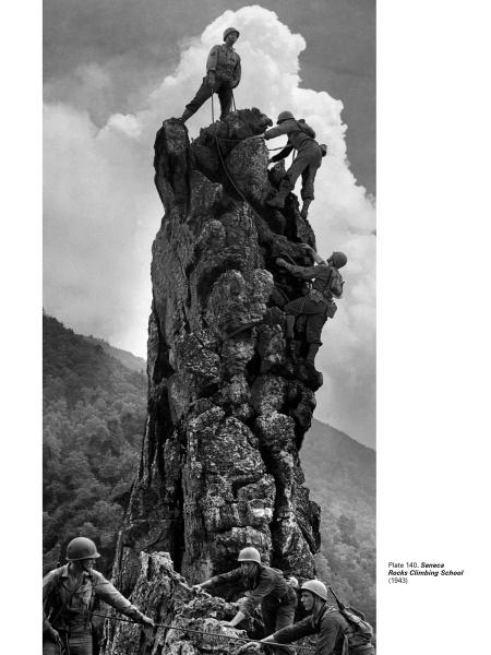 In Bodine's Industry by Schiffer Publishing, Ltd., soldiers in uniform scale a jagged rock with ropes, one standing victorious atop—echoing classic American photography. Trees and clouds form a dramatic backdrop.