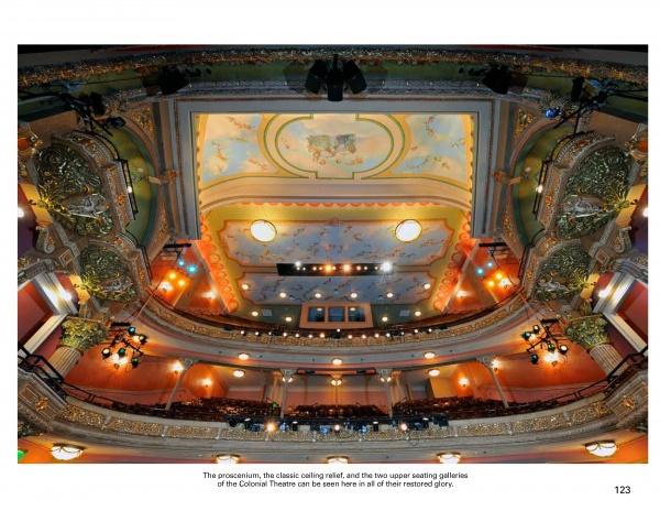 A vibrant wide-angle shot of a restored theater interior from "Along Route 7" by Schiffer Publishing, Ltd., features ornate balconies, golden accents, decorative ceiling, and rows of seats—capturing the charm of small-town Americana.