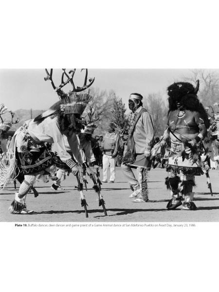 In "Pueblo Dancing" by Schiffer Publishing, Ltd., three Indigenous men in traditional Pueblo attire perform a ceremonial dance outdoors—one in a buffalo headdress, another in deer antlers—honoring Native American heritage as spectators watch.