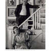 A black-and-white photo of a man in glasses on a staircase above a seated woman, surrounded by art, embodies the creative spirit celebrated in "Perspectives on the Provincetown Art Colony" by Schiffer Publishing, Ltd.