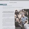 A group of men and women in business and casual attire sit and stand in a classroom, listening to a bearded man near a sculpture featured in "Robert Engman" by Schiffer Publishing, Ltd.; some attendees are taking notes.