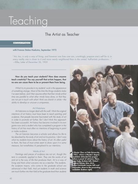 A group of men and women in business and casual attire sit and stand in a classroom, listening to a bearded man near a sculpture featured in "Robert Engman" by Schiffer Publishing, Ltd.; some attendees are taking notes.