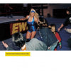 A woman in a shiny blue wrestling outfit enters an arena, smiling at fans. Caption: From "Hard Boys and Bad Girls" by Schiffer Publishing, Ltd., 2004.