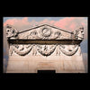 Ghosts in the Cemetery II by Schiffer Publishing, Ltd. features a stone façade with classical carvings—two sculpted faces on each corner, garlands, and a floral medallion—set beneath pink clouds, evoking cemetery photography.