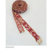The Norwegian Pick-Up Bandweaving by Schiffer Publishing, Ltd. features a long, woven band with red and white geometric patterns and fringed ends, displayed rolled up on a plain white background.