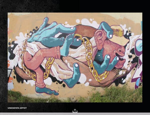 Street Talking" by Schiffer Publishing, Ltd. is a colorful mural featuring disjointed blue hands, pink arms and feet, gold chains, a stylized face with a yellow cap, all on a beige background with white splashes and grass along the bottom edge.