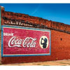 A vintage brick building with a faded Coca-Cola mural and colorful awnings graces the cover of "Back Roads of the Great Plains" by Schiffer Publishing, Ltd.—ideal for fans of landscape photography and classic Americana.