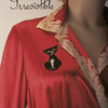 A mannequin displays vintage-inspired elegance in a red dress with a beige lace collar and black cat brooch. “Irresistible: The Art of Lingerie, 1920s-1980s” by Schiffer Publishing, Ltd. appears in cursive at the top left.