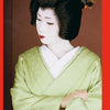 A woman evokes Kyoto geisha as seen in "Geisha & Maiko of Kyoto" by Schiffer Publishing, Ltd., wearing a pale green kimono, white undergarment, white face makeup, red lips, and decorated black hair styled with ornate hairpieces.