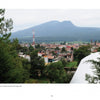 View of Santa Clara del Cobre, famed for hammered copper vessels featured in "Mexican Arts Series: Hammered Copper" by Schiffer Publishing, Ltd., with buildings, trees, a red and white radio tower, and a forested mountain under a cloudy sky.