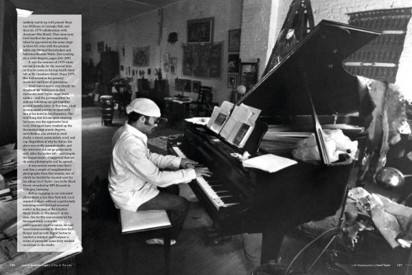 A man in a cap plays piano amid paintings and sculptures in an art-filled studio, as featured in "Jazz in Available Light" by Schiffer Publishing, Ltd.—a book capturing the creative essence of jazz through striking photography.