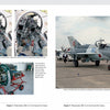 A book spread from "The MiG-21" by Schiffer Publishing, Ltd. features a MiG-21 cockpit interior on the left, a MiG-21 combat jet on outdoor display to the right, and a jet engine on a stand in the lower left corner.